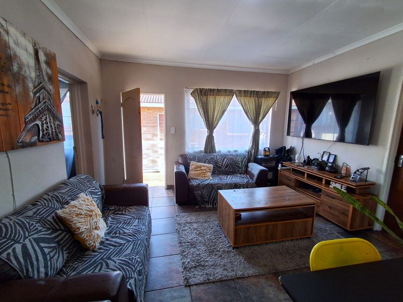 A comfortable living room featuring tiled flooring and direct access to the exterior through a sliding door.