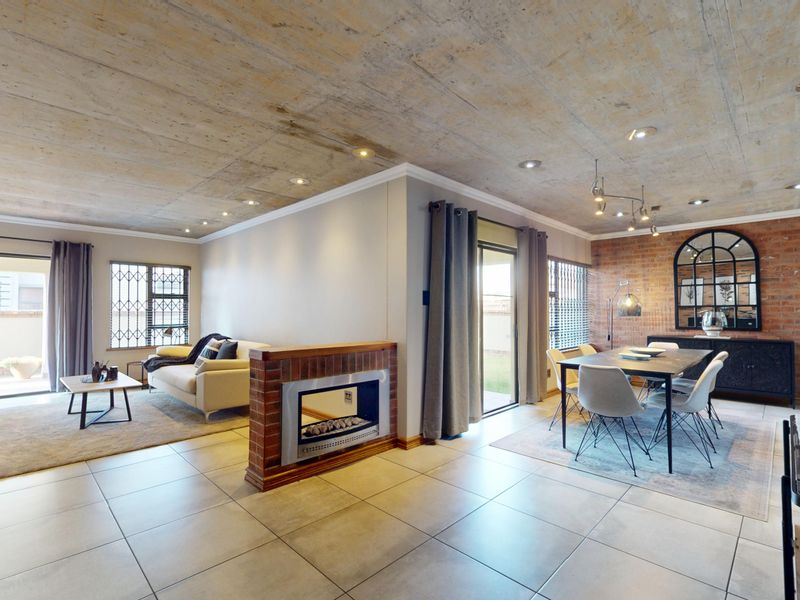 Spacious open-plan living and dining area featuring an exposed concrete ceiling, brick feature wall, built-in fireplace, and large sliding doors leading to the exterior.