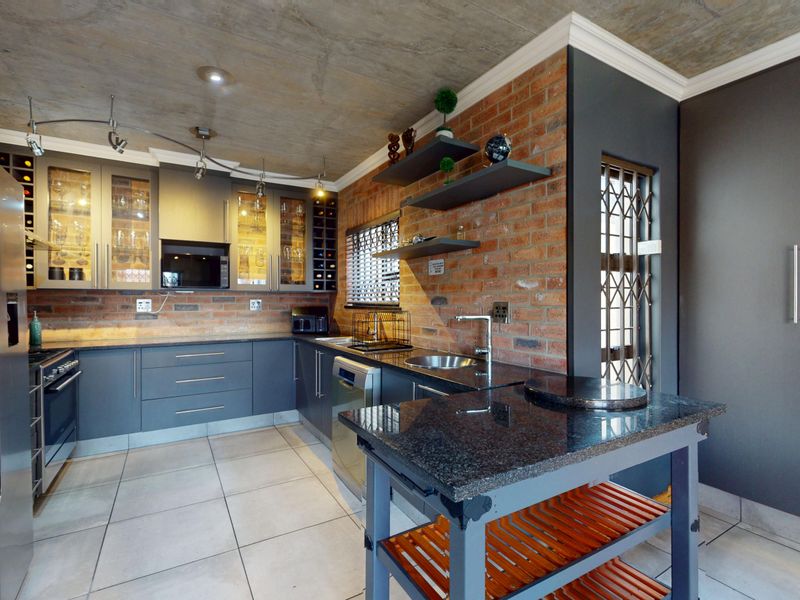 Modern kitchen featuring exposed brick walls, concrete ceiling, granite countertops, and ample built-in cabinetry with integrated appliances.