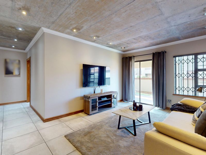Modern living room featuring an exposed concrete ceiling, tiled floors, a brick feature wall, and direct access to an outdoor area via sliding doors.