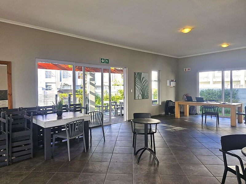 A spacious, open-plan clubhouse area featuring tiled flooring, large sliding glass doors providing natural light, and recessed ceiling lighting.