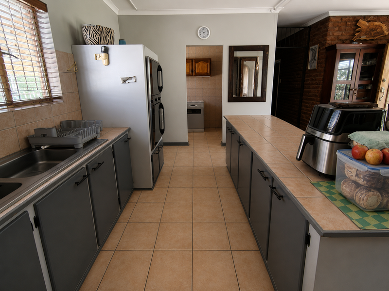 A functional kitchen featuring tiled countertops, built-in double oven, and ample cabinetry, with a scullery area visible through the doorway.