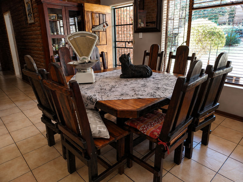 Dining room featuring exposed brick walls, ceramic floor tiles, and natural light through large windows with security blinds.