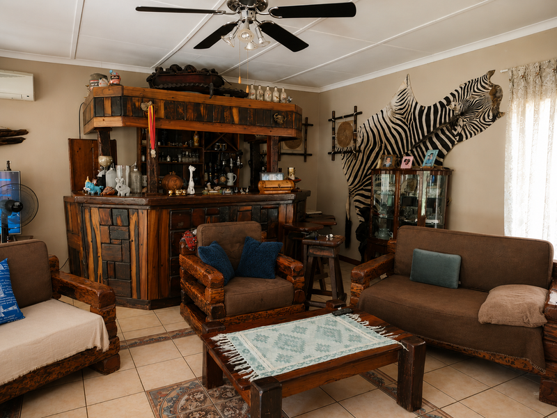 A rustic-style home bar area featuring a substantial built-in wooden bar counter, tiled flooring, and a ceiling fan.
