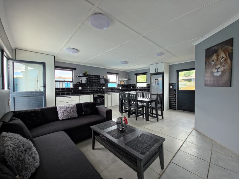 Spacious open-plan living and kitchen area featuring modern black cabinetry, subway tile backsplash, tiled flooring, and direct access to the exterior.