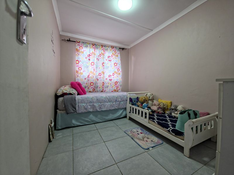 A functional bedroom featuring tiled flooring and neutral wall finishes, providing a blank canvas for potential interior updates.