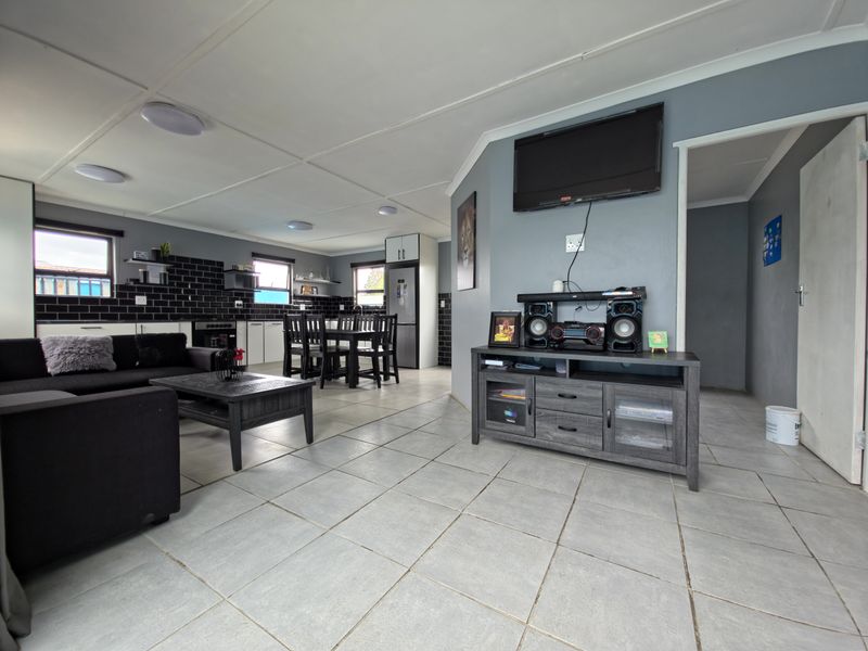 Open-plan living and kitchen area featuring tiled flooring, modern subway tile backsplash, and functional built-in cabinetry, creating a cohesive and practical living space.