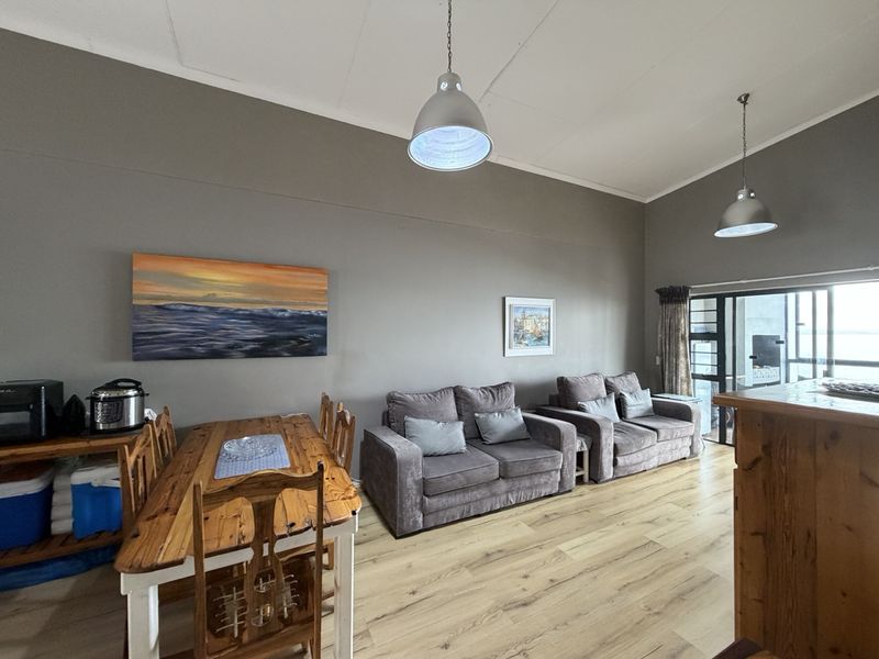 Open plan living and dining area featuring laminate flooring, pendant lighting, and access to an outdoor space through a sliding glass door.