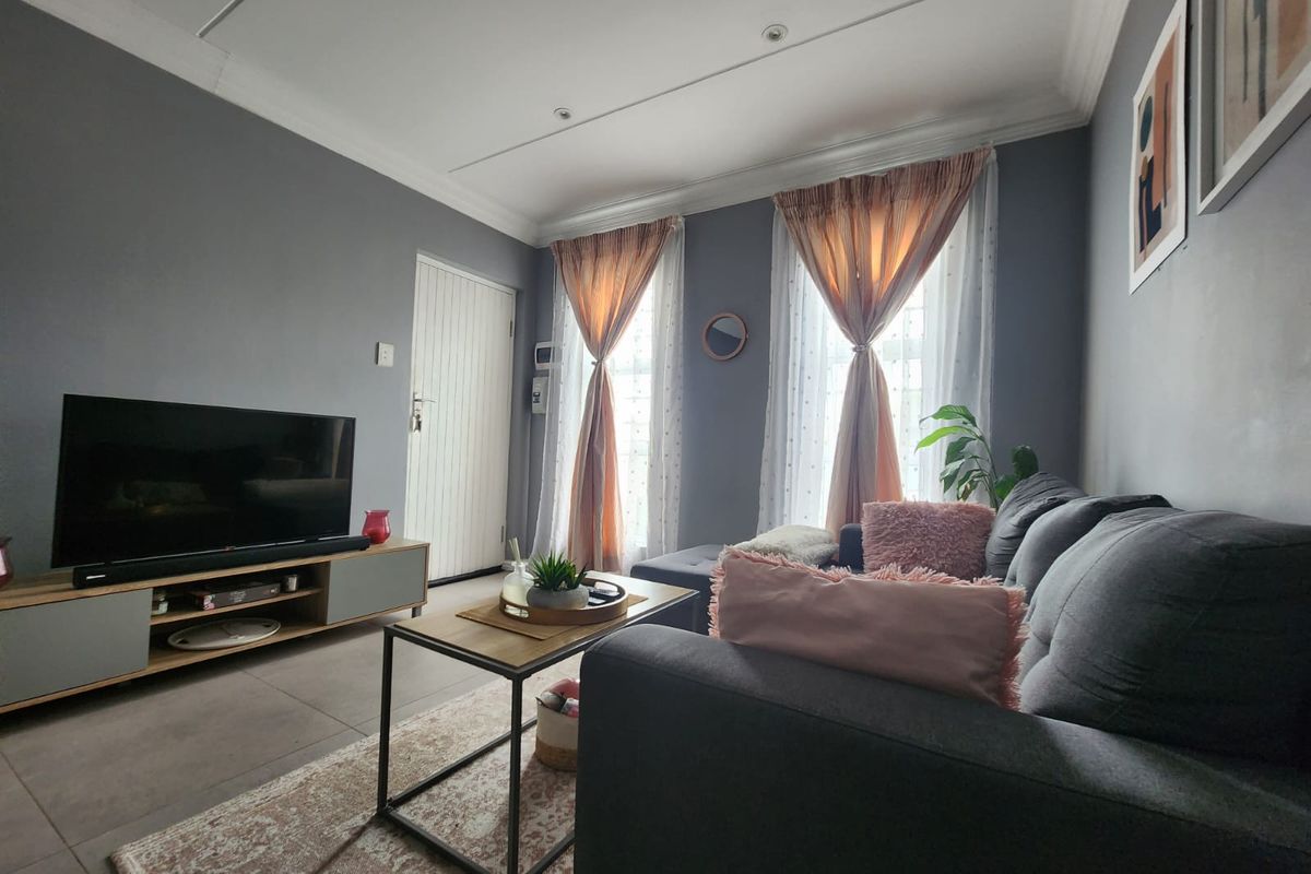 A well-maintained living room featuring tiled flooring, recessed ceiling lighting, and decorative cornicing, creating a comfortable and functional living space.