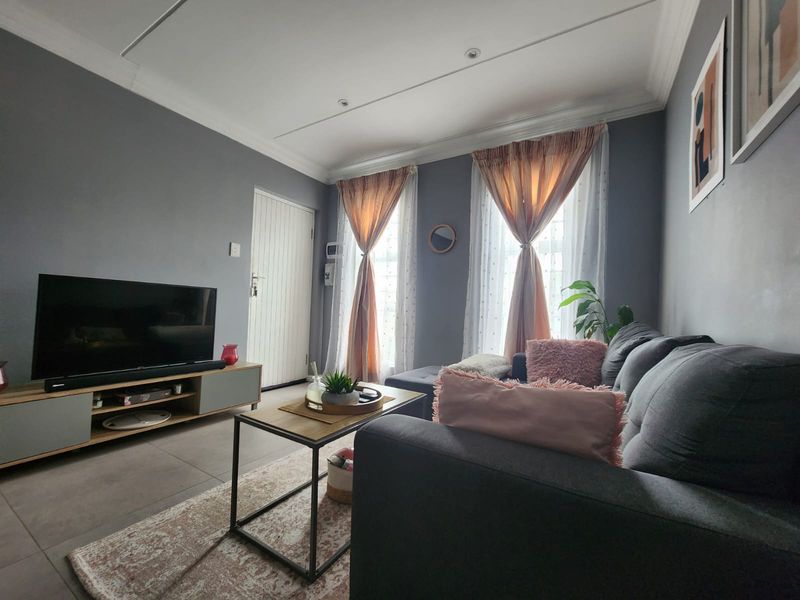 A well-maintained living room featuring tiled flooring, recessed ceiling lighting, and decorative cornicing, creating a comfortable and functional living space.