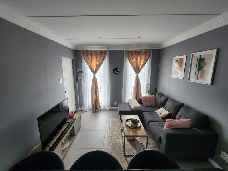 A well-maintained living room featuring tiled flooring, decorative cornicing, and recessed lighting, providing a comfortable and functional space.