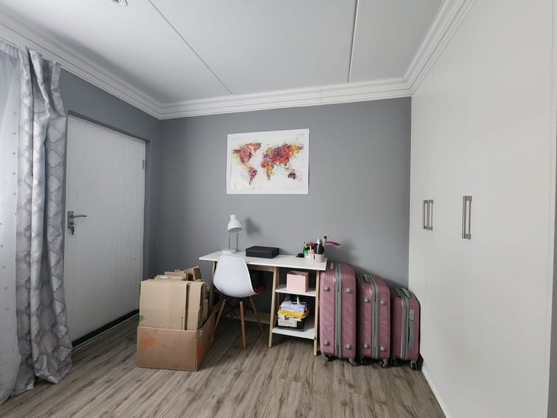 A bedroom featuring laminate flooring, built-in cupboards, and decorative ceiling cornicing, providing a neutral base for personalization.