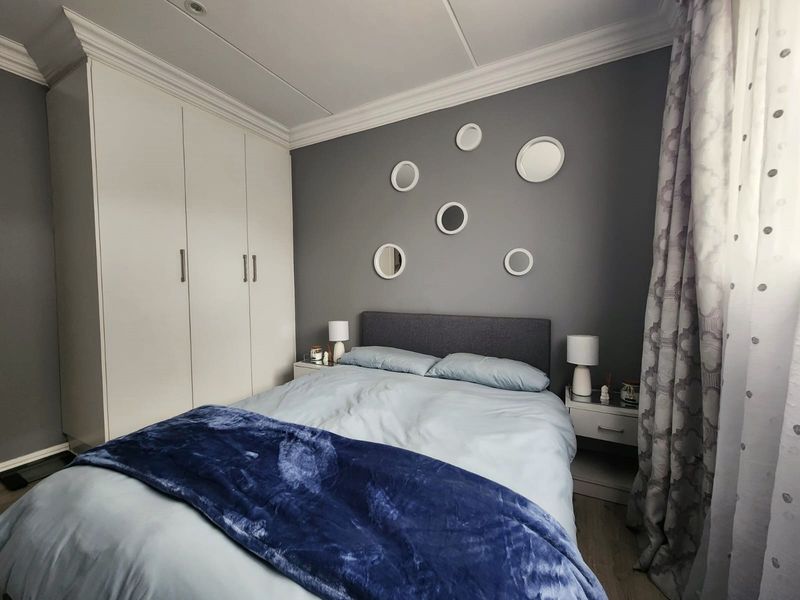 A well-maintained bedroom featuring built-in cupboards, crown molding, and recessed ceiling lighting, creating a clean and functional living space.