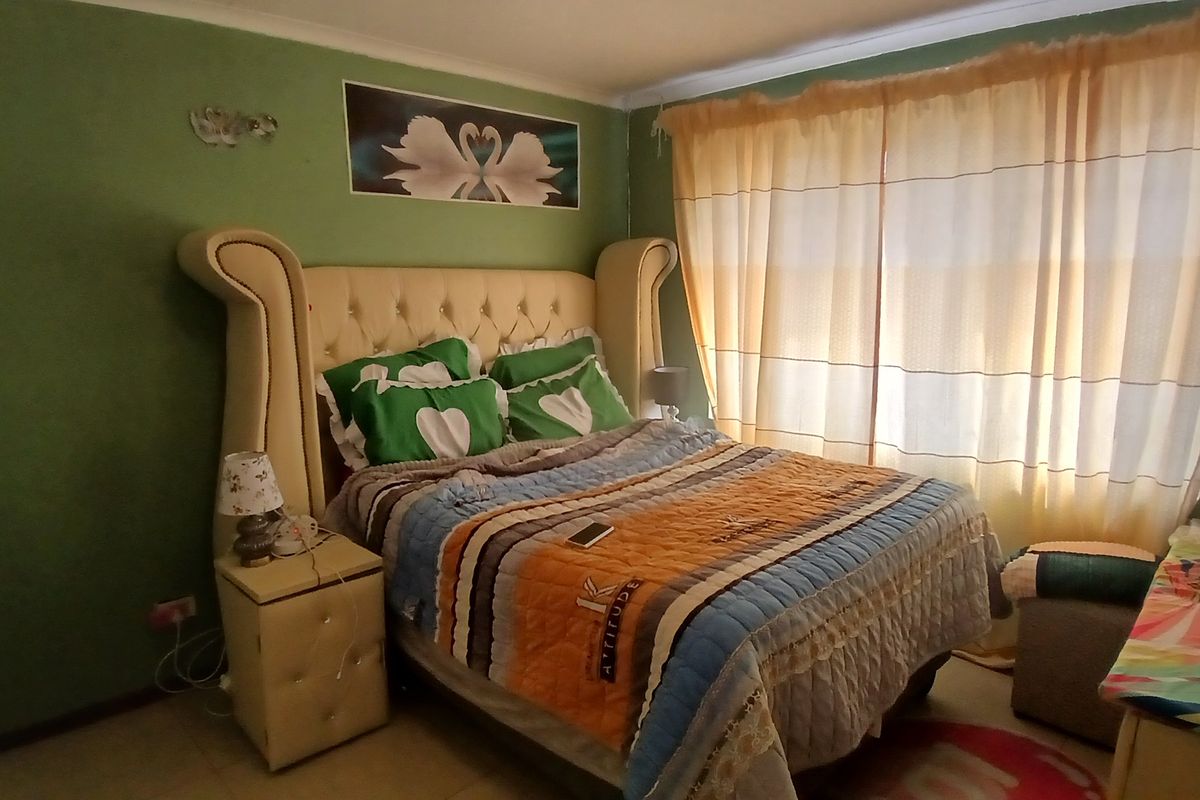 A standard bedroom featuring tiled flooring and large window with curtain rails, providing a functional space for rest.