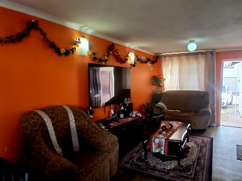 A living room area featuring orange walls, coving, and wall-mounted lighting, with direct access to the exterior.