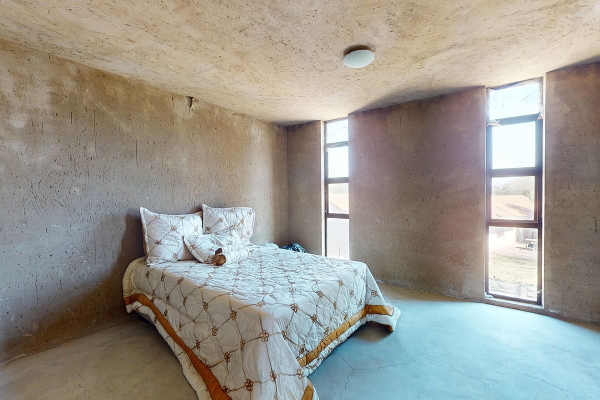A bedroom featuring raw concrete walls, ceiling, and flooring with vertical windows, offering a minimalist industrial aesthetic ready for finishing touches.