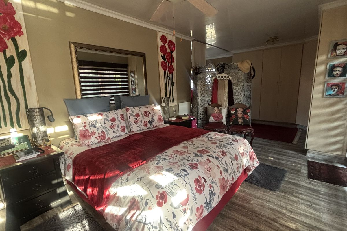 Spacious bedroom featuring laminate flooring, built-in cupboards, and a ceiling fan, offering a comfortable and functional living space.