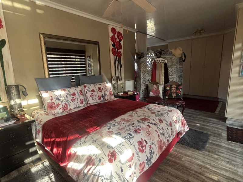 Spacious bedroom featuring laminate flooring, built-in cupboards, and a ceiling fan, offering a comfortable and functional living space.