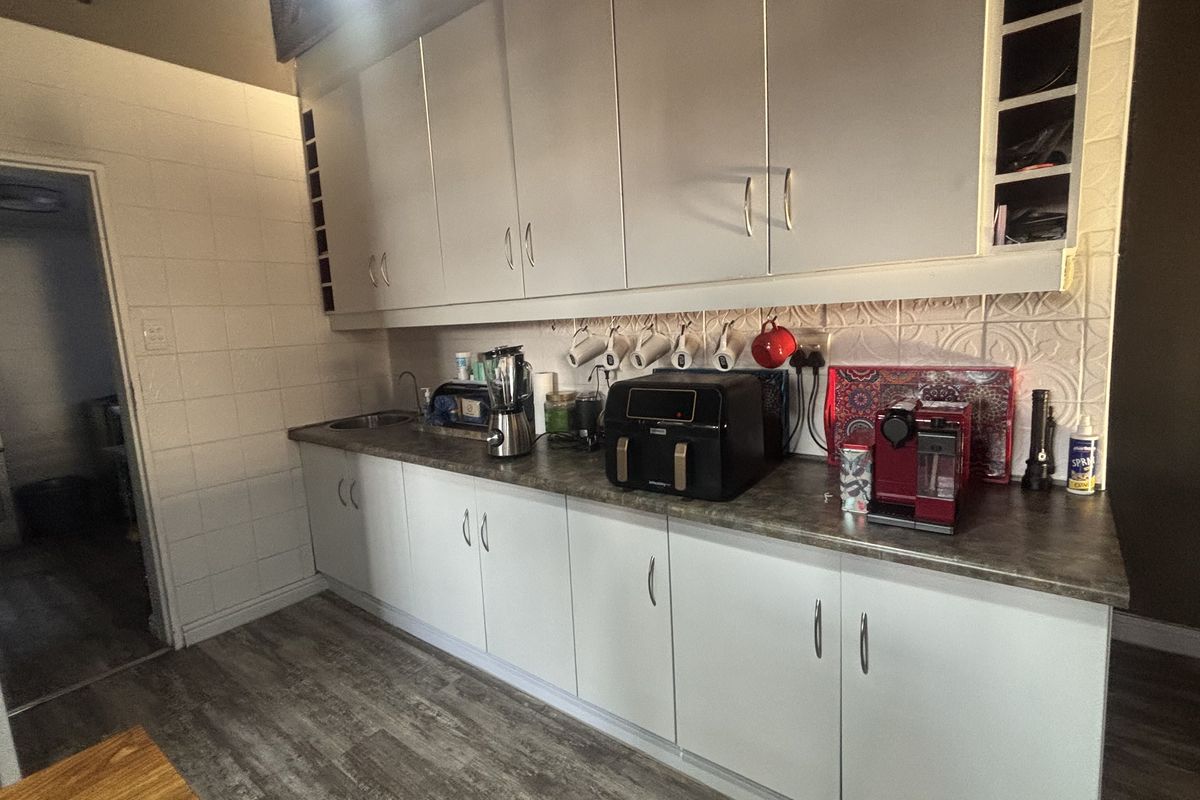 A functional kitchen featuring white cabinetry, a tiled backsplash, and laminate countertops with wood-look flooring.