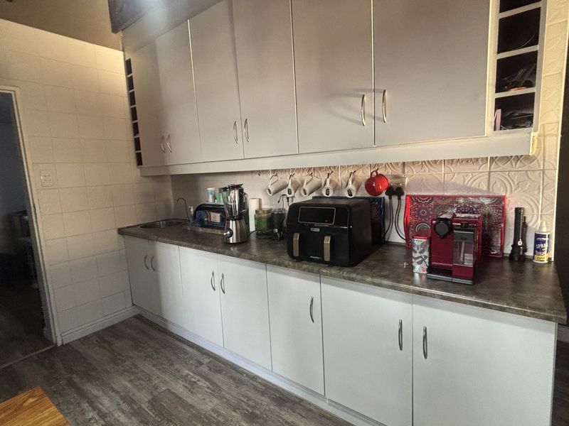 A functional kitchen featuring white cabinetry, a tiled backsplash, and laminate countertops with wood-look flooring.
