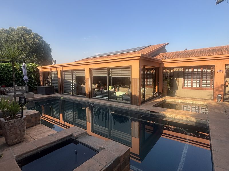 A well-maintained outdoor pool area featuring a swimming pool, tiled patio space, and direct access to the home through large sliding glass doors.