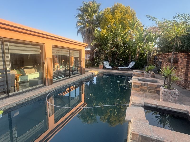Outdoor pool area featuring a swimming pool, paved surround, built-in brick planters, and direct access to the home through large sliding glass doors.