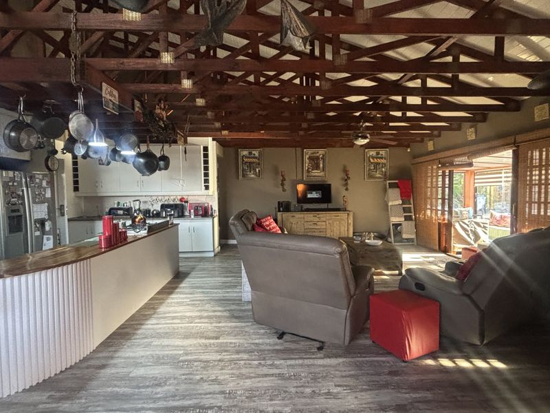 Spacious open-plan living area featuring exposed timber roof trusses, a functional kitchen with island, and sliding doors leading to the outdoor space.