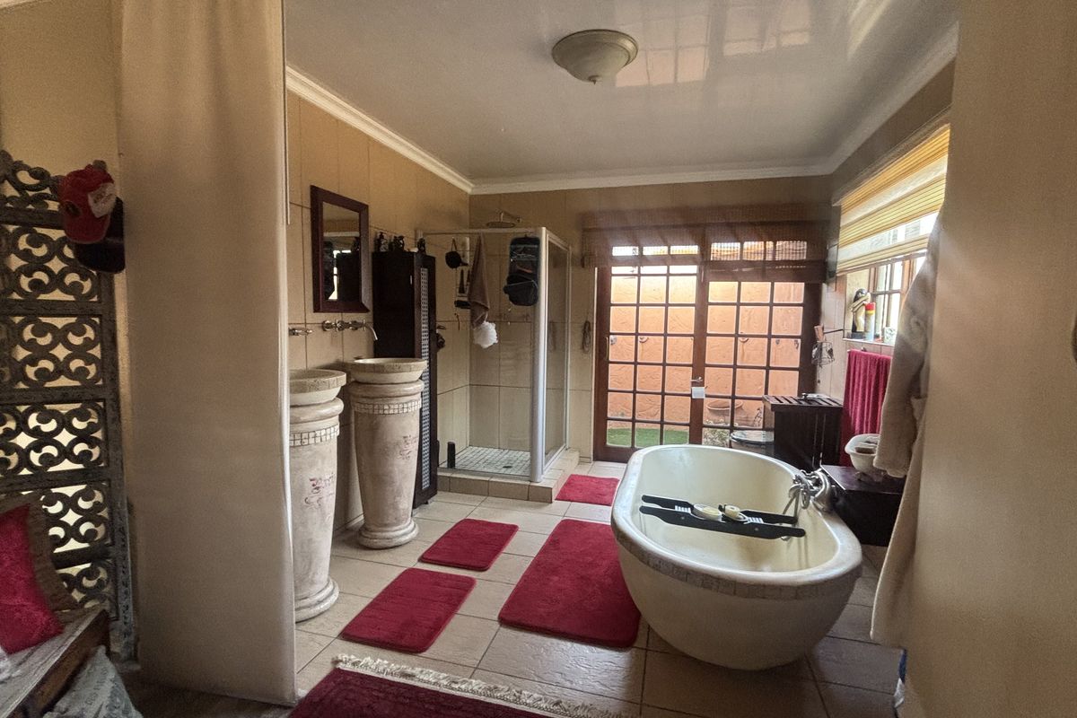Spacious bathroom featuring a freestanding bathtub, dual pedestal washbasins, a separate shower enclosure, and direct access to an outdoor area through french doors.