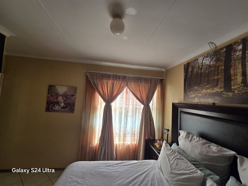 A bedroom featuring tiled flooring, a central ceiling light, and window treatments. The space offers a functional layout ready for cosmetic updates.