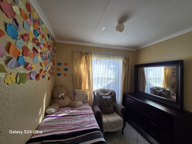 A bedroom featuring tiled flooring and a central ceiling light fixture, with natural light entering through the window.