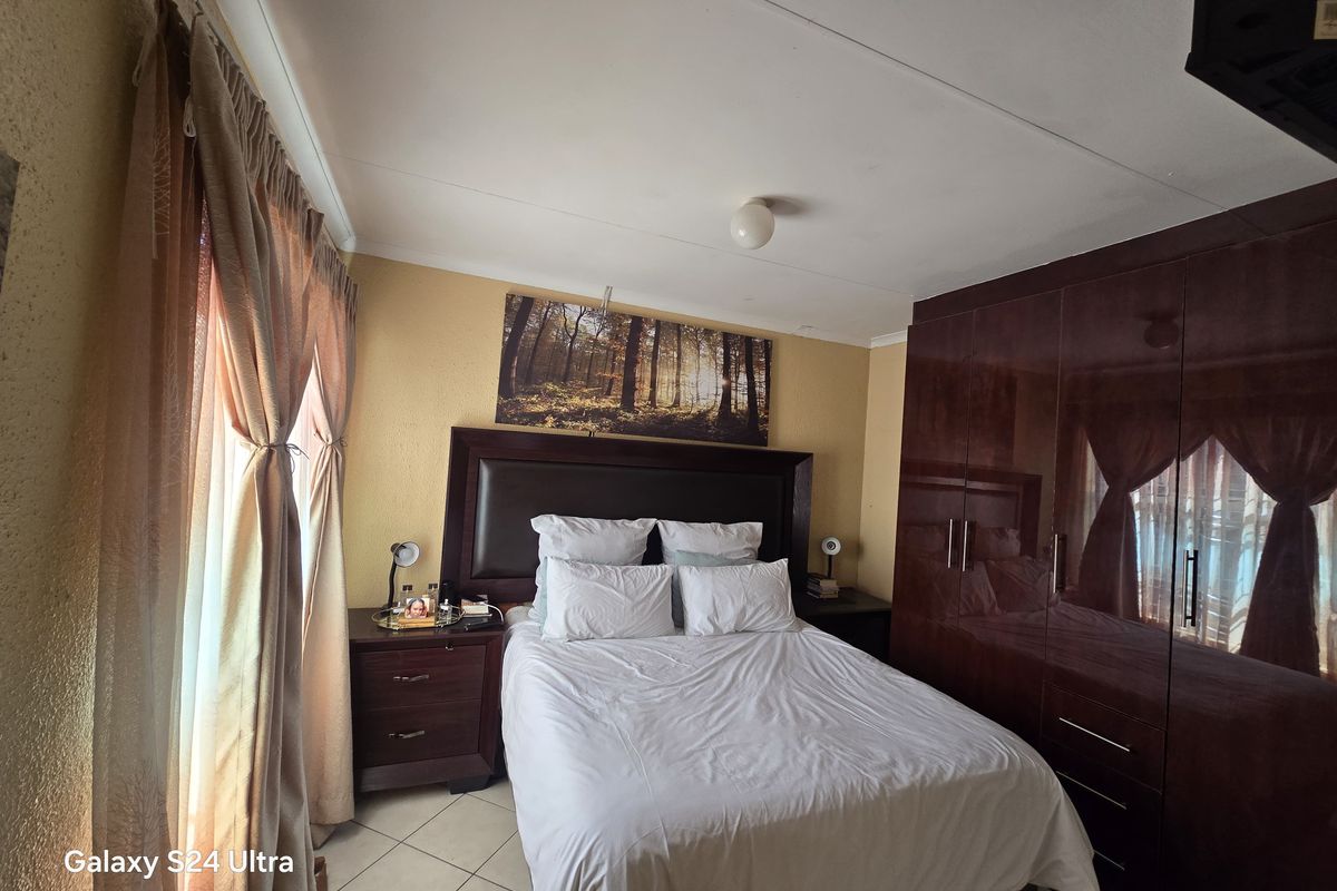 A functional bedroom featuring built-in dark wood cupboards and tiled flooring, offering a comfortable and practical living space.
