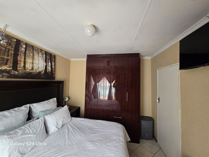 A bedroom featuring a built-in dark wood wardrobe, tiled flooring, and coved ceiling details.