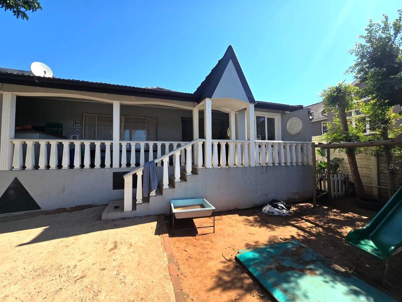Rear view of the property featuring a covered patio with a balustrade, concrete stairs, and a tiled roof structure.