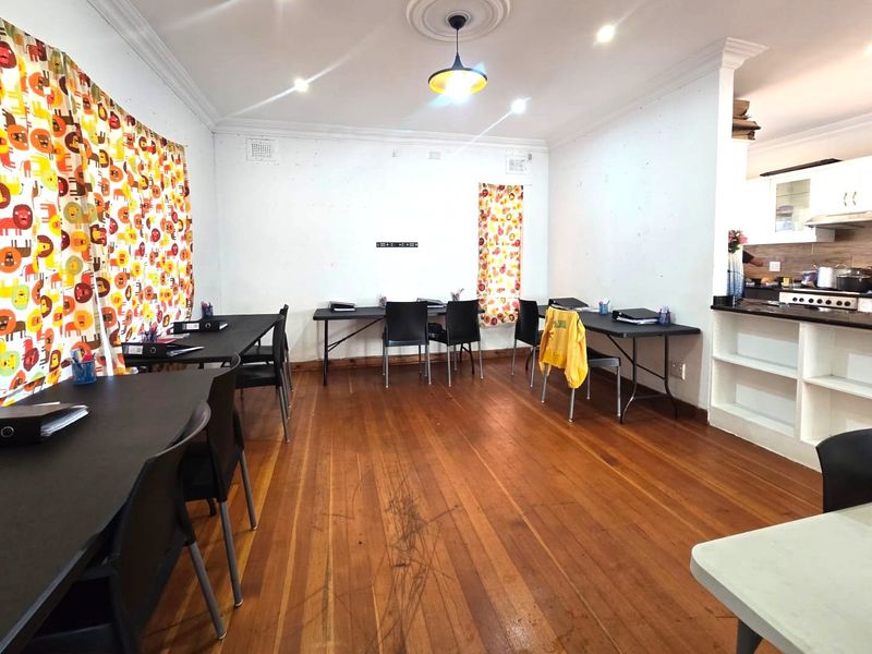 Open plan living and kitchen area featuring hardwood flooring, crown molding, and built-in kitchen cabinetry with an extractor fan.
