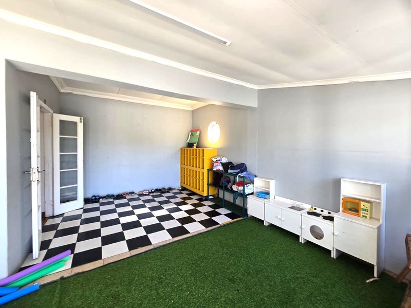 A multi-purpose utility room featuring a mix of checkerboard tile and artificial grass flooring with a unique circular window.