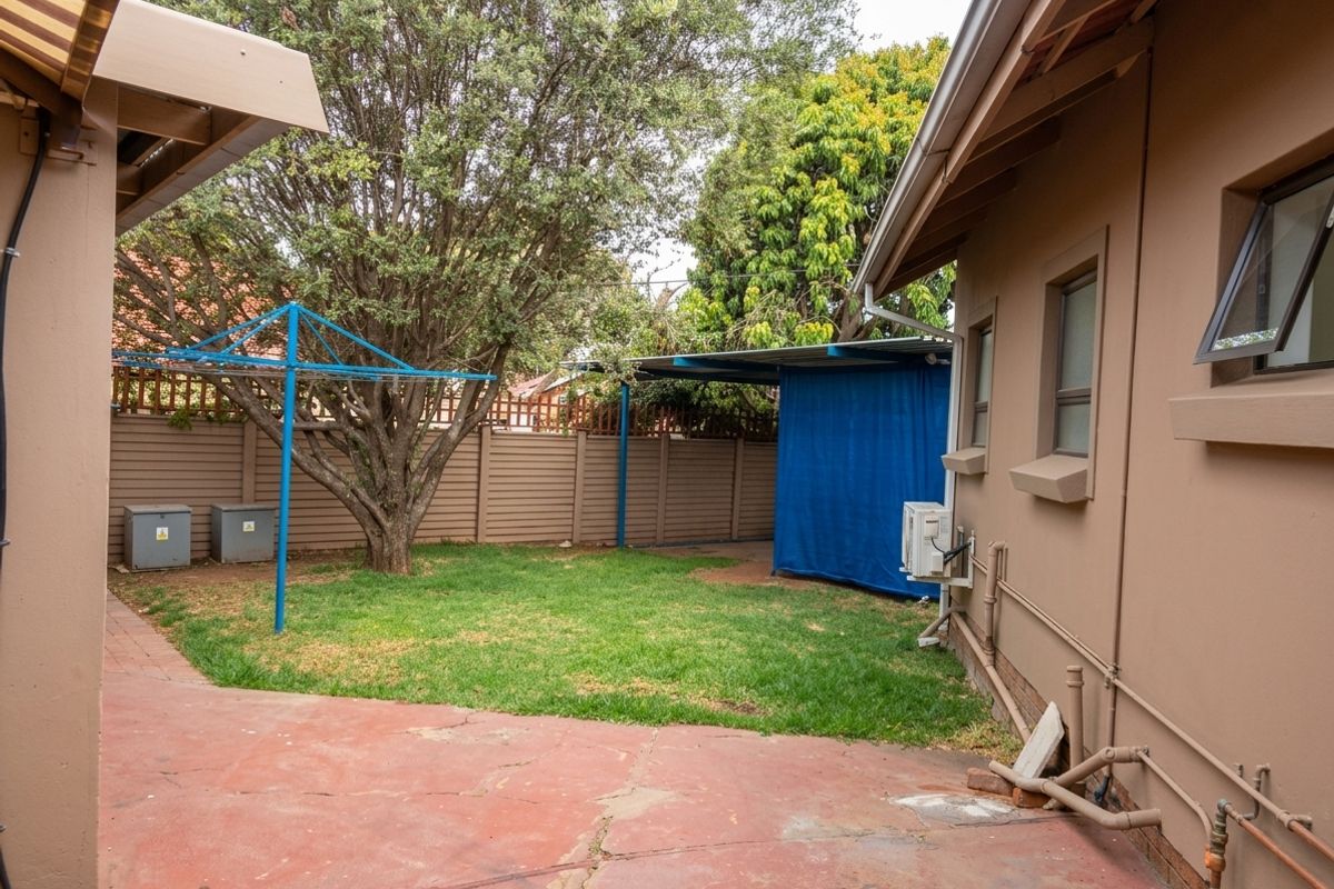 Rear garden area featuring a paved patio, lawn, rotary clothesline, and boundary fencing, providing a functional outdoor space.