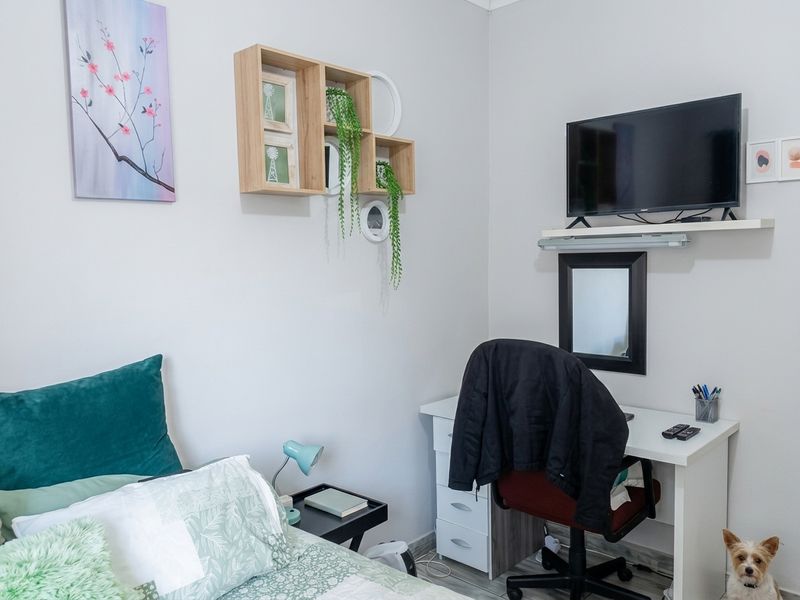 A well-maintained bedroom featuring neutral wall tones and durable laminate flooring, providing a comfortable and functional living space.