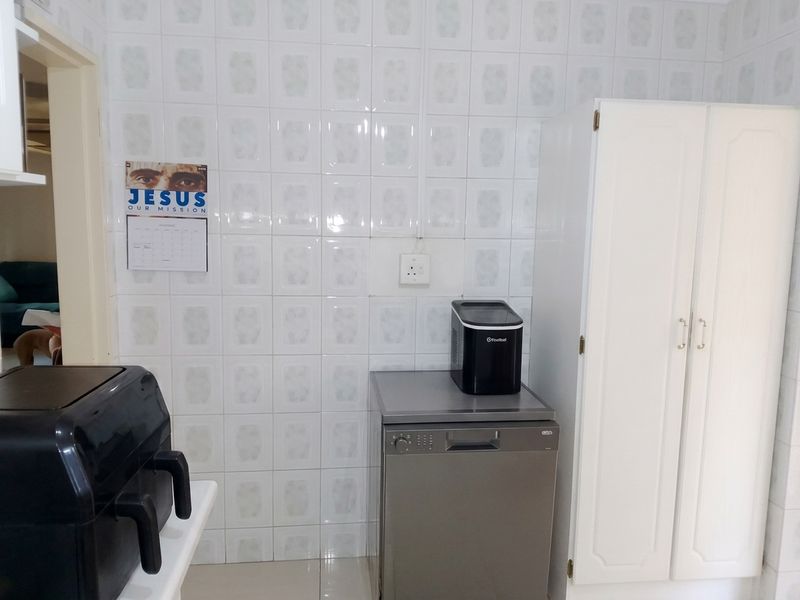 A functional kitchen area featuring tiled walls, a built-in storage cupboard, and space for appliances.
