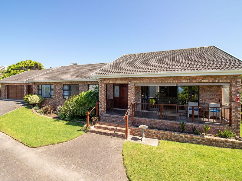 A well-maintained face brick family home featuring a paved driveway, double garage, and a covered front patio overlooking a landscaped garden.