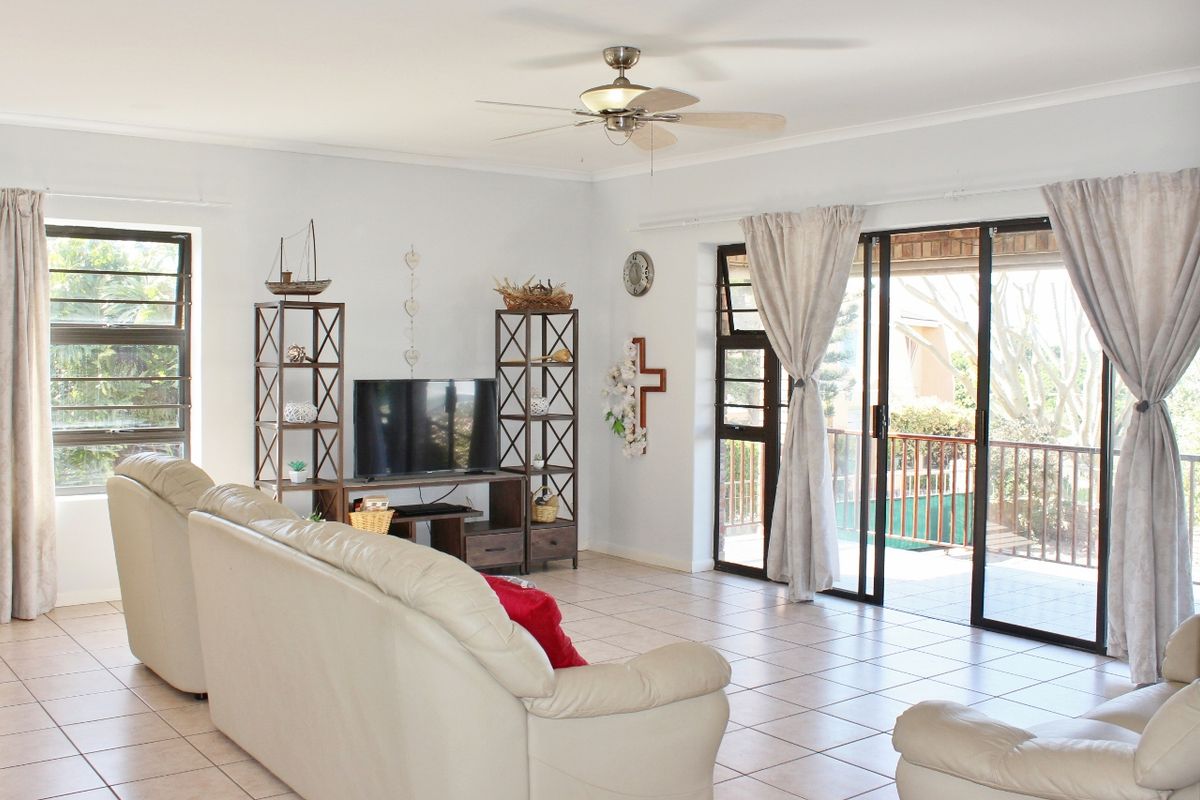 Spacious living room featuring tiled flooring, a ceiling fan, and large sliding glass doors providing direct access to an outdoor patio area.
