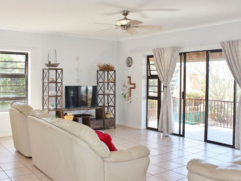 Spacious living room featuring tiled flooring, a ceiling fan, and large sliding glass doors providing direct access to an outdoor patio area.