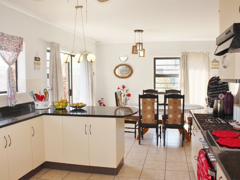 Open-plan kitchen and dining area featuring granite countertops, built-in cabinetry, and tiled flooring with direct access to the outdoor space via sliding doors.