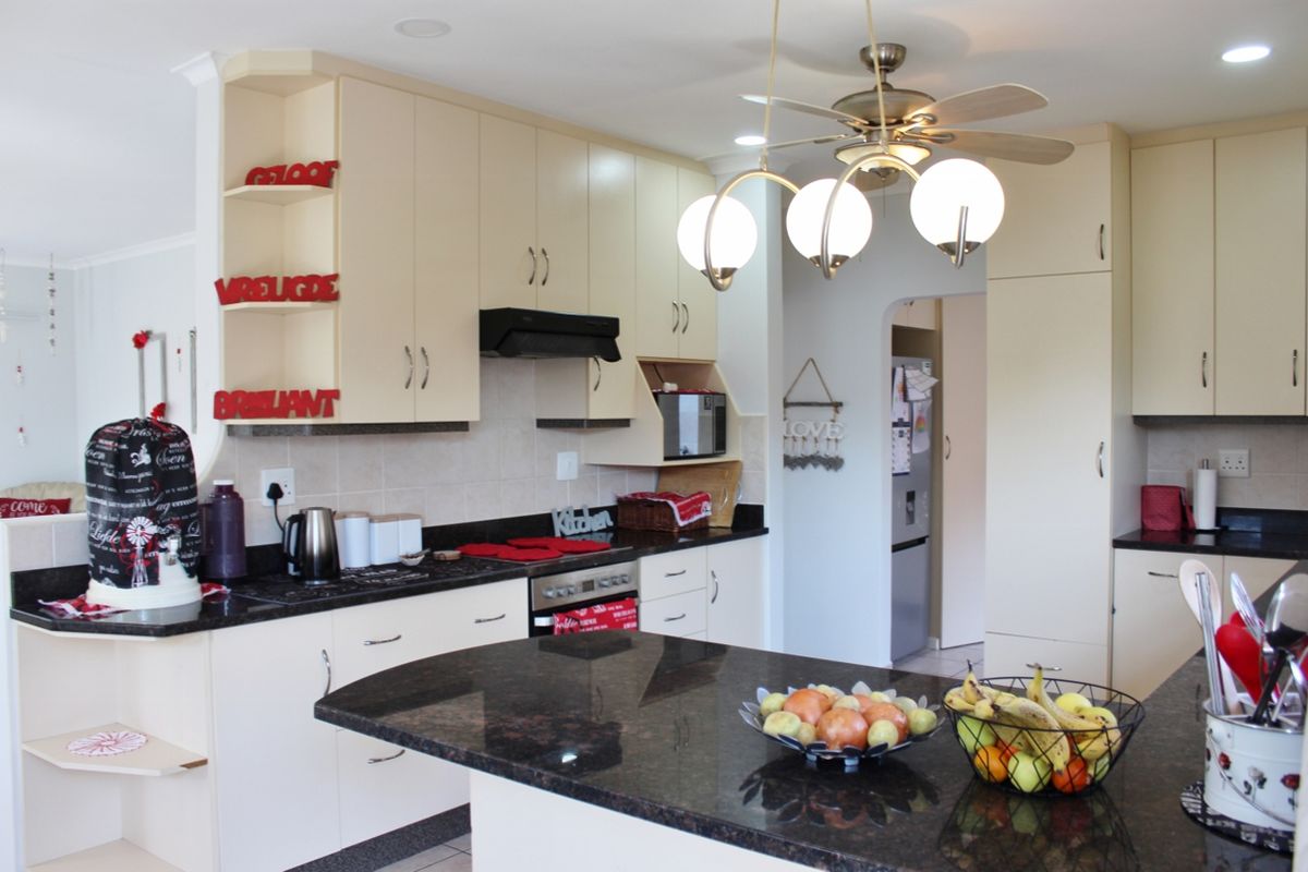 A functional kitchen featuring granite countertops, ample built-in cabinetry, a tiled backsplash, and a central island, providing a practical workspace.