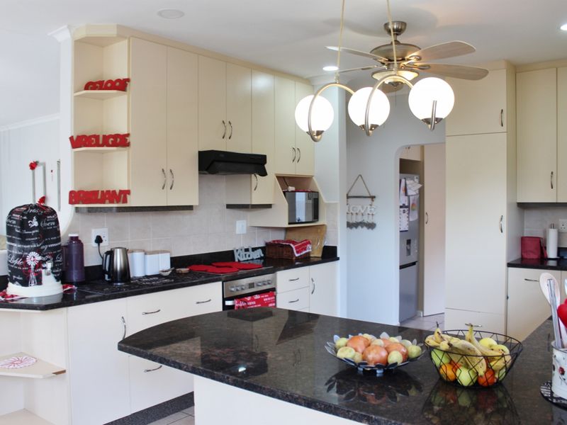 A functional kitchen featuring granite countertops, ample built-in cabinetry, a tiled backsplash, and a central island, providing a practical workspace.