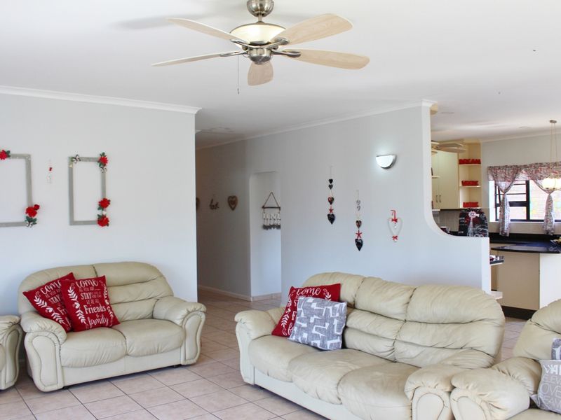 Open plan living area featuring tiled flooring, a ceiling fan, and a semi-open kitchen with built-in cabinetry and countertops.