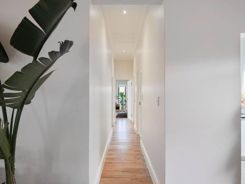 A bright and clean hallway featuring modern timber flooring and recessed downlighting, providing a seamless transition between living areas.