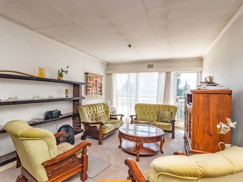 A living room featuring built-in shelving with a brick support pillar, carpet flooring, and access to an outdoor balcony through a sliding glass door.