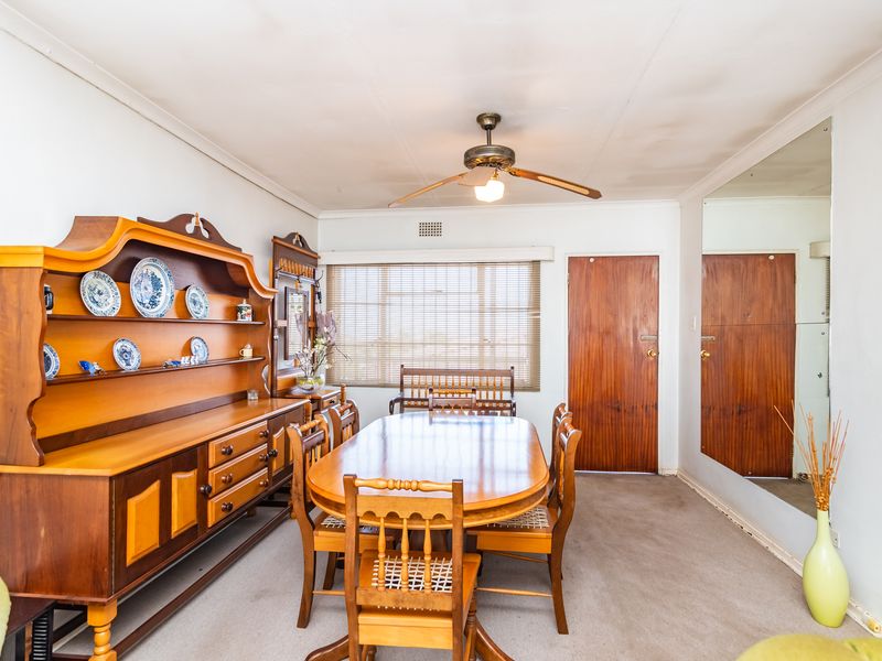 Dining room featuring a ceiling fan, venetian blinds, and a large wall-mounted mirror. The space requires cosmetic updates to the ceiling and flooring.