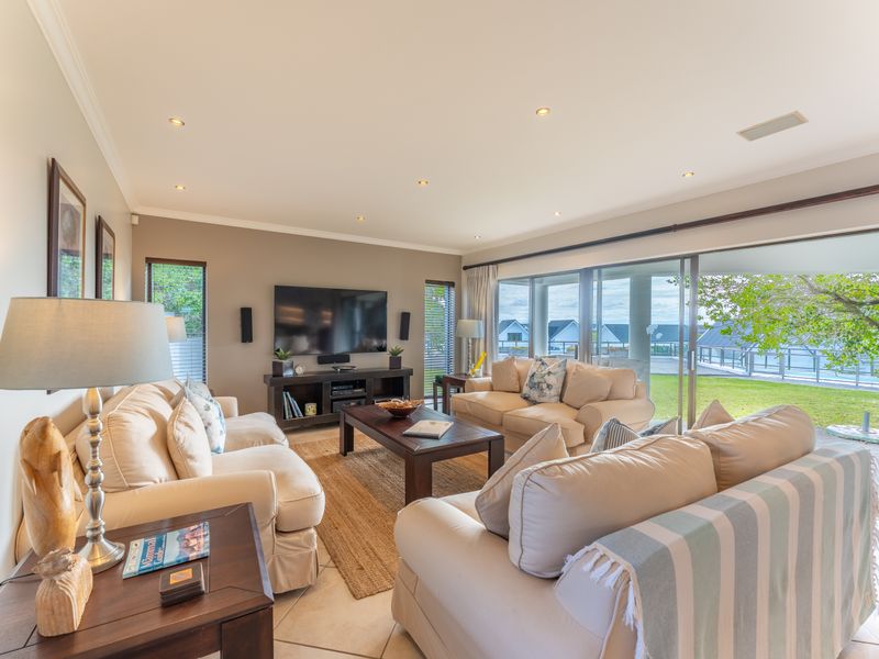 Spacious living room featuring tiled floors, recessed lighting, and large sliding glass doors that provide seamless access to the outdoor patio and garden area.