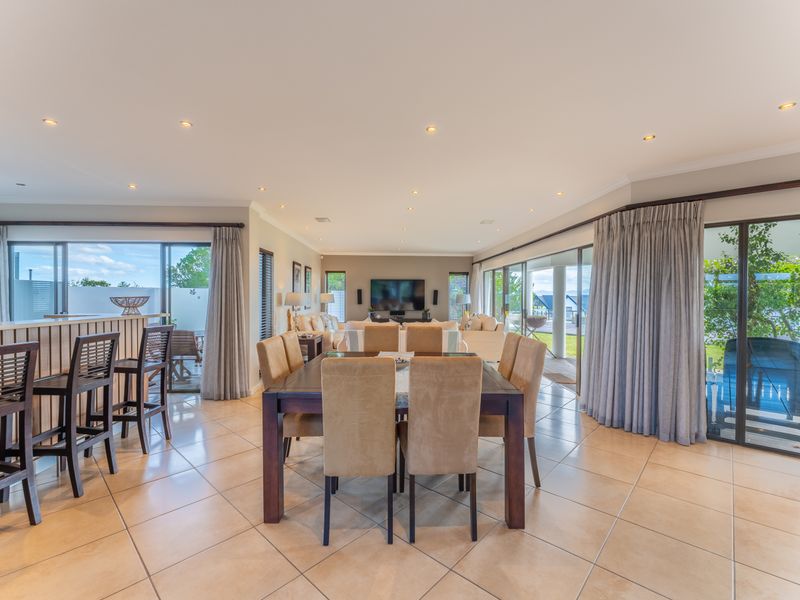 Spacious open-plan living and dining area featuring large sliding glass doors, tiled flooring, and recessed lighting, offering seamless indoor-outdoor flow.